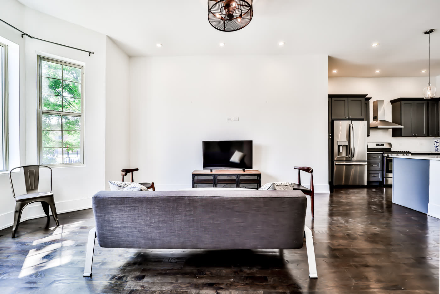 Renovated apartment living room and kitchen with dark floors and a modern kitchen island.